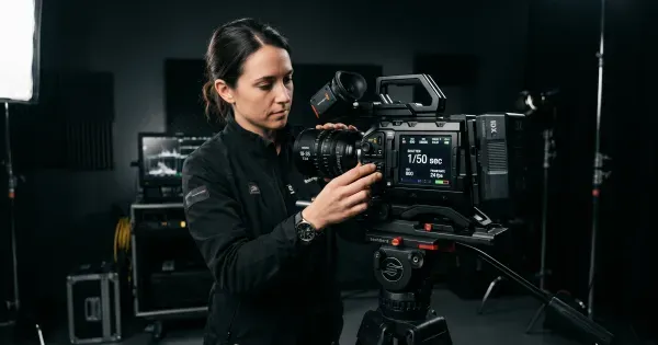 Camera operator adjusting shutter speed settings on a cinema camera on set